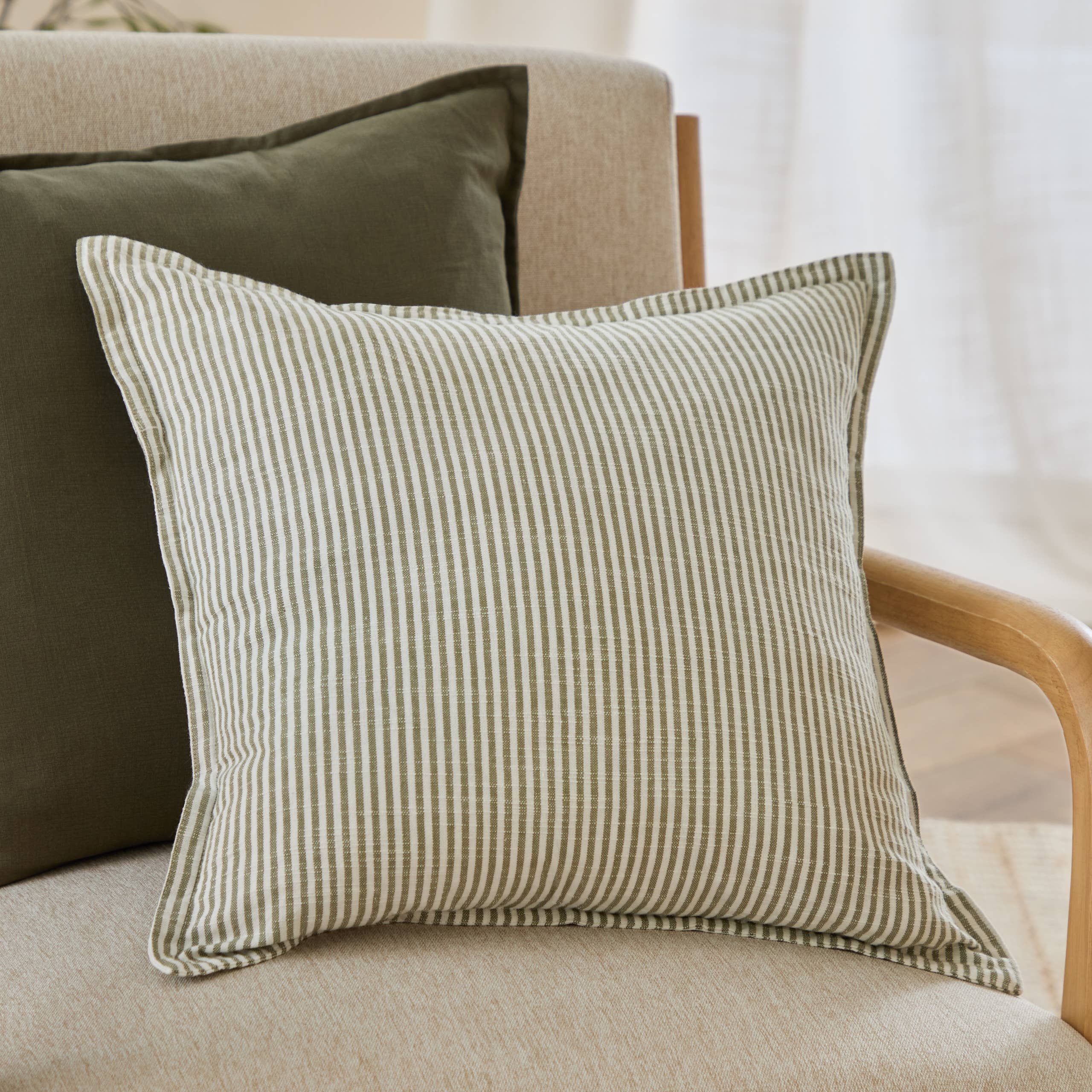 Truro striped cotton slub cushion with reversible narrow stripe design and Oxford border, styled on a neutral sofa in a relaxed country-inspired living room.