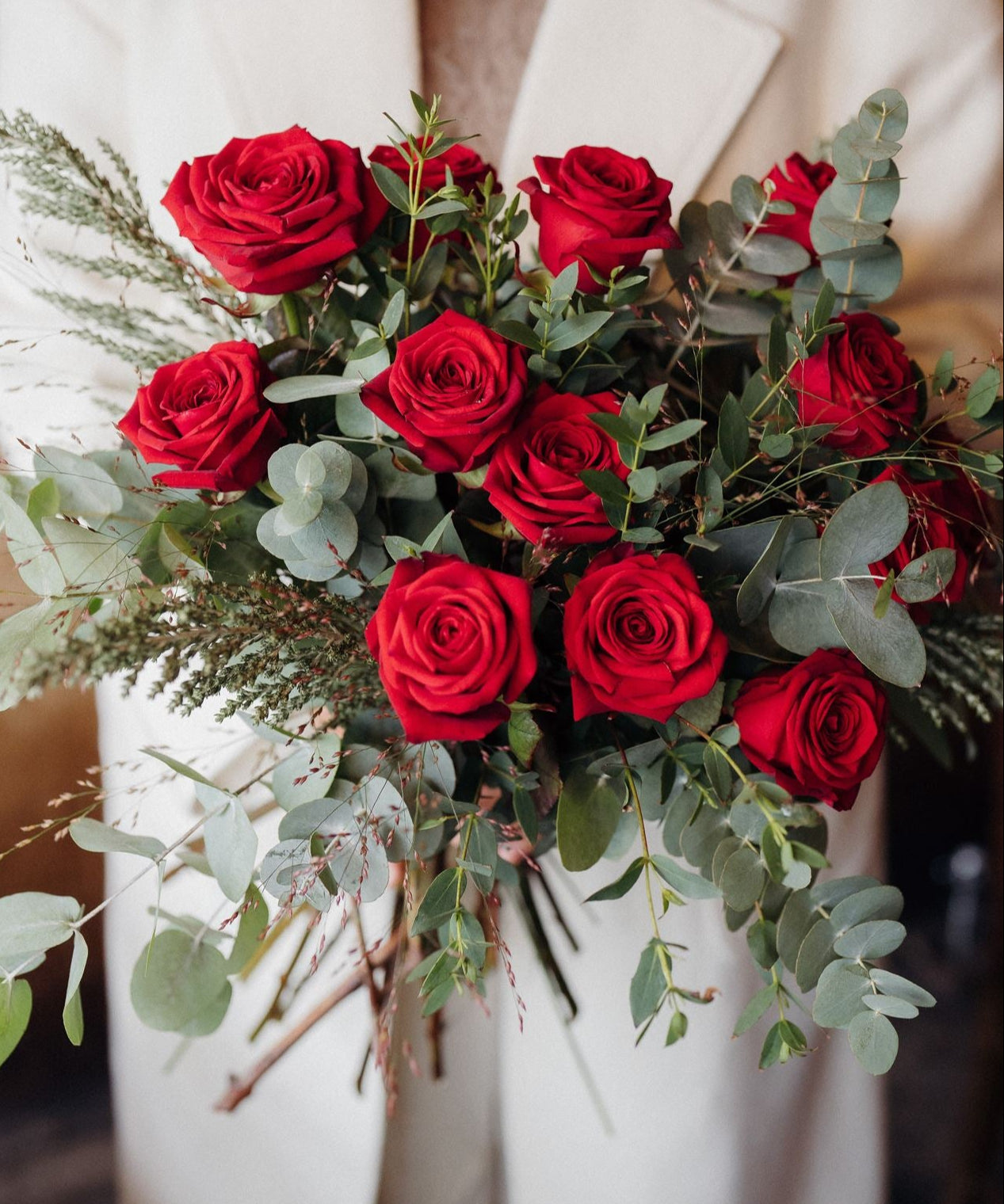 The Winter Cherry Roses luxury bouquet of long-stemmed Red Explorer roses with fragrant green eucalyptus.
