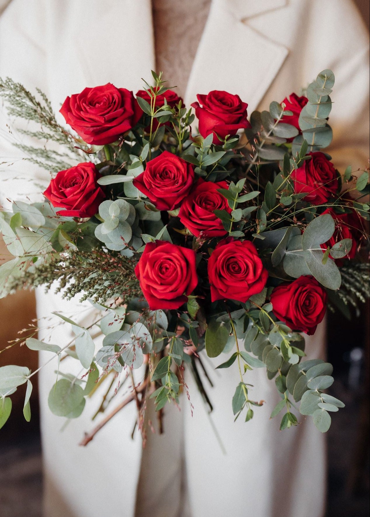 The Winter Cherry Roses luxury bouquet of long-stemmed Red Explorer roses with fragrant green eucalyptus.