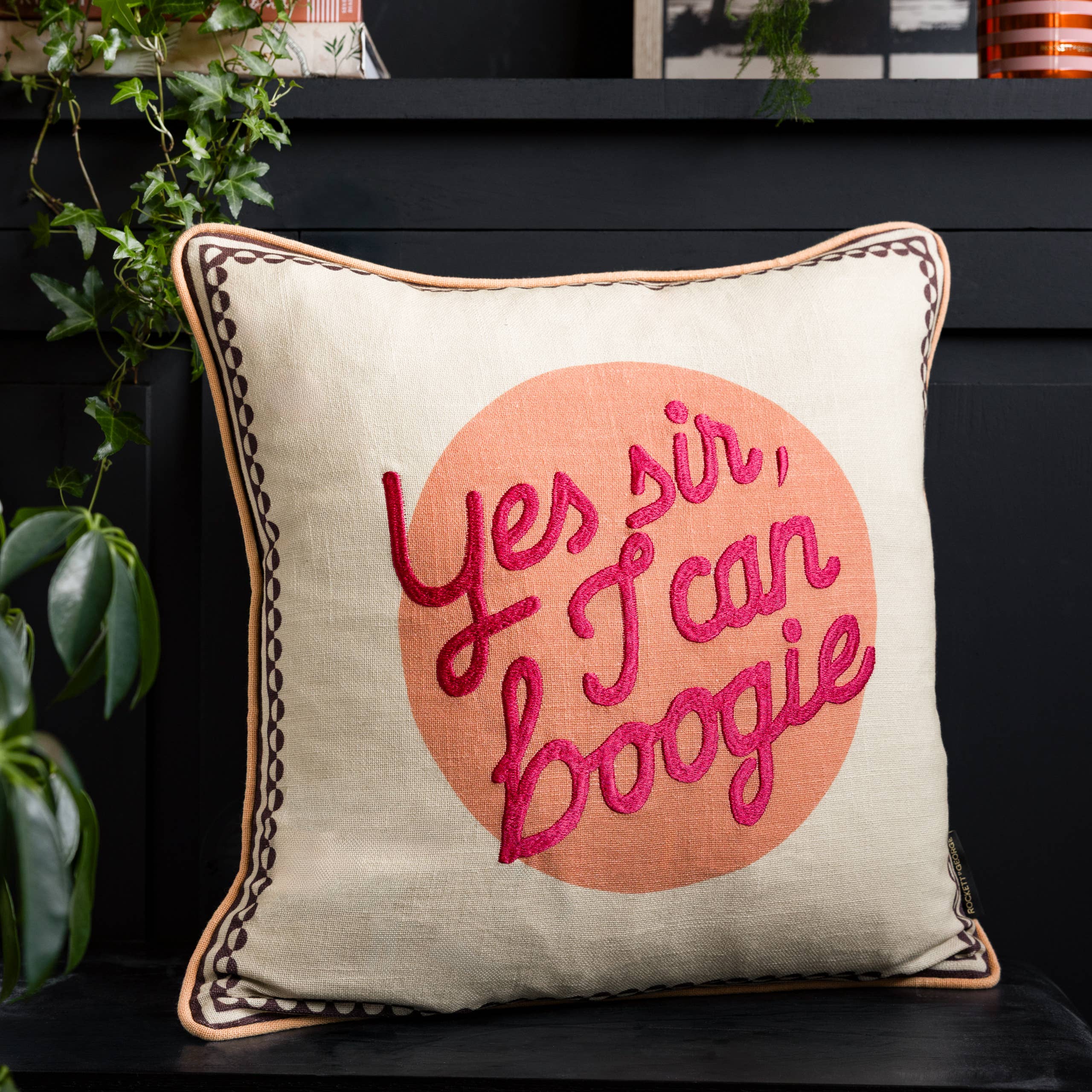 Yes Sir I Can Boogie Peach Cotton Slub Cushion in cream and peach on a sofa, featuring a playful slogan and textured cotton fabric.