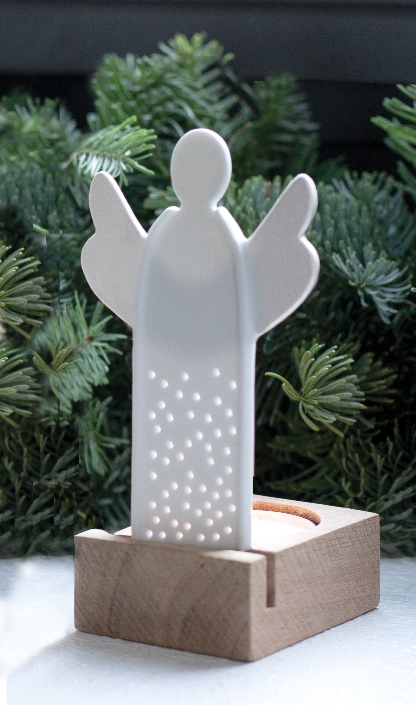 A white porcelain angel tealight holder with decorative holes