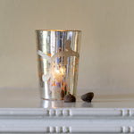 A silver candle holder with an etched floral design 