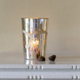 A silver candle holder with an etched floral design 