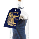 Archivist blue extra-long safety matches with white tips in a reusable glass bottle featuring a letterpress-foiled elephant label and cork stopper.