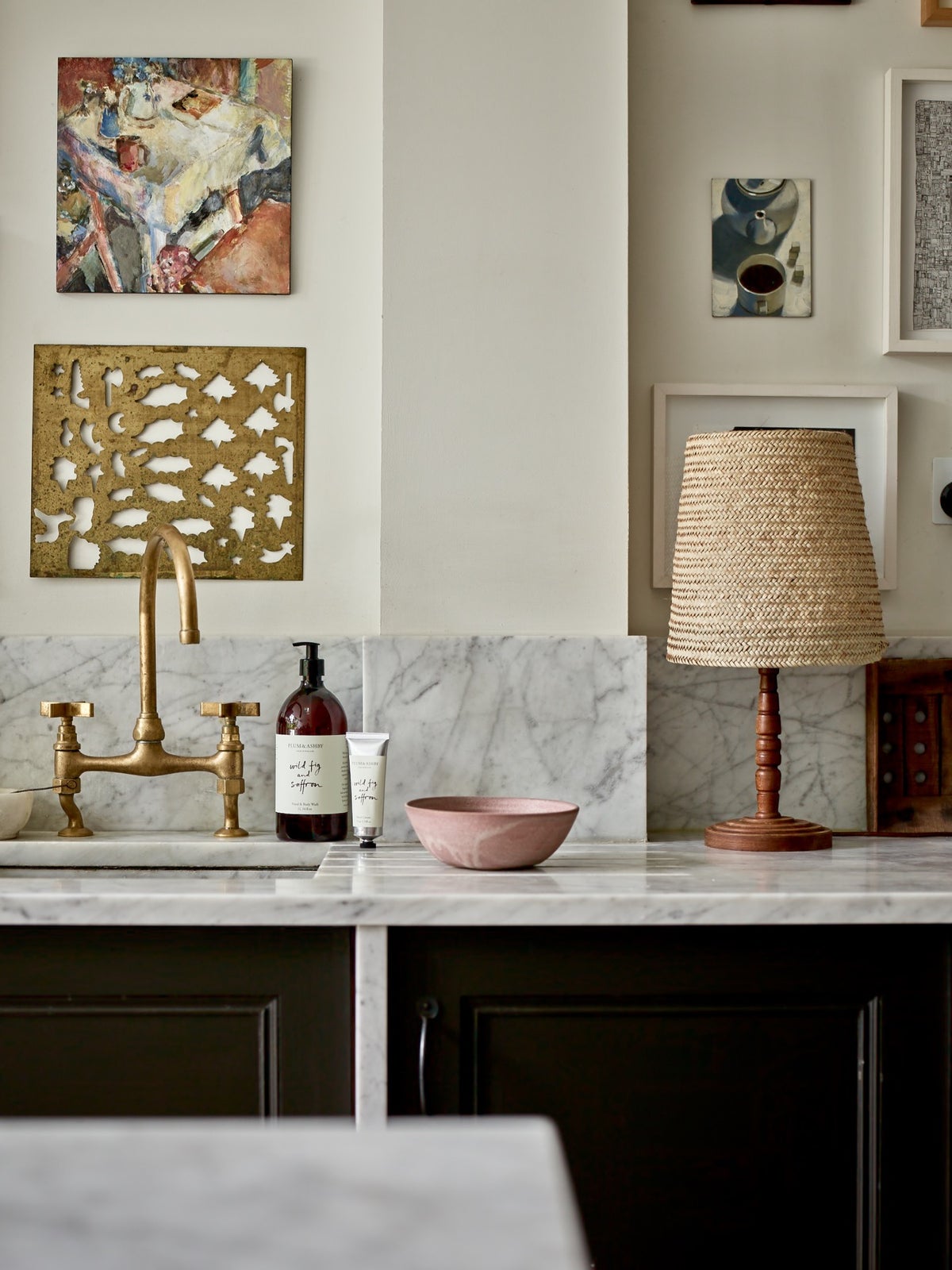1 Litre bottle of Plum & Ashby Wild Fig & Saffron Hand & Body Wash on a kitchen countertop with a marble backdrop and a gold-patterned napkin holder in the background.