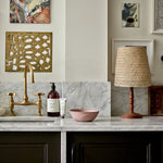 1 Litre bottle of Plum & Ashby Wild Fig & Saffron Hand & Body Wash on a kitchen countertop with a marble backdrop and a gold-patterned napkin holder in the background.