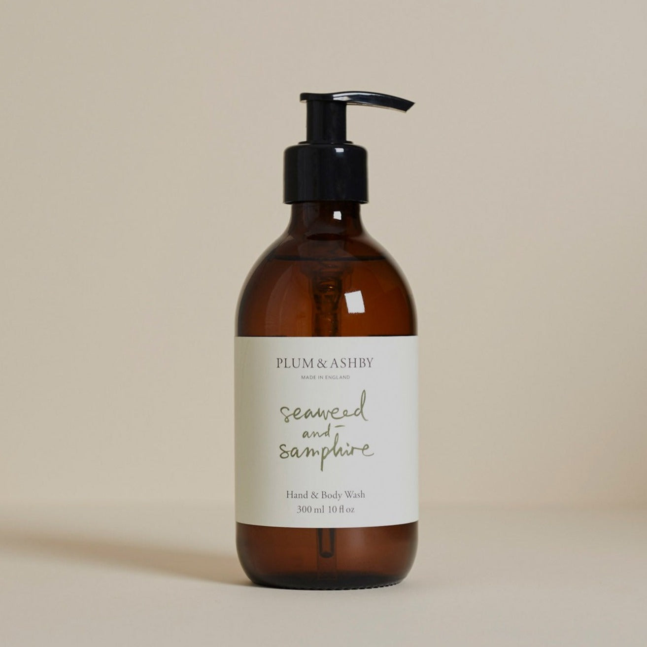 A pump bottle of Plum & Ashby Seaweed & Samphire Hand & Body Wash with a beige label and brown glass.