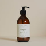 A pump bottle of Plum & Ashby Seaweed & Samphire Hand & Body Wash with a beige label and brown glass.