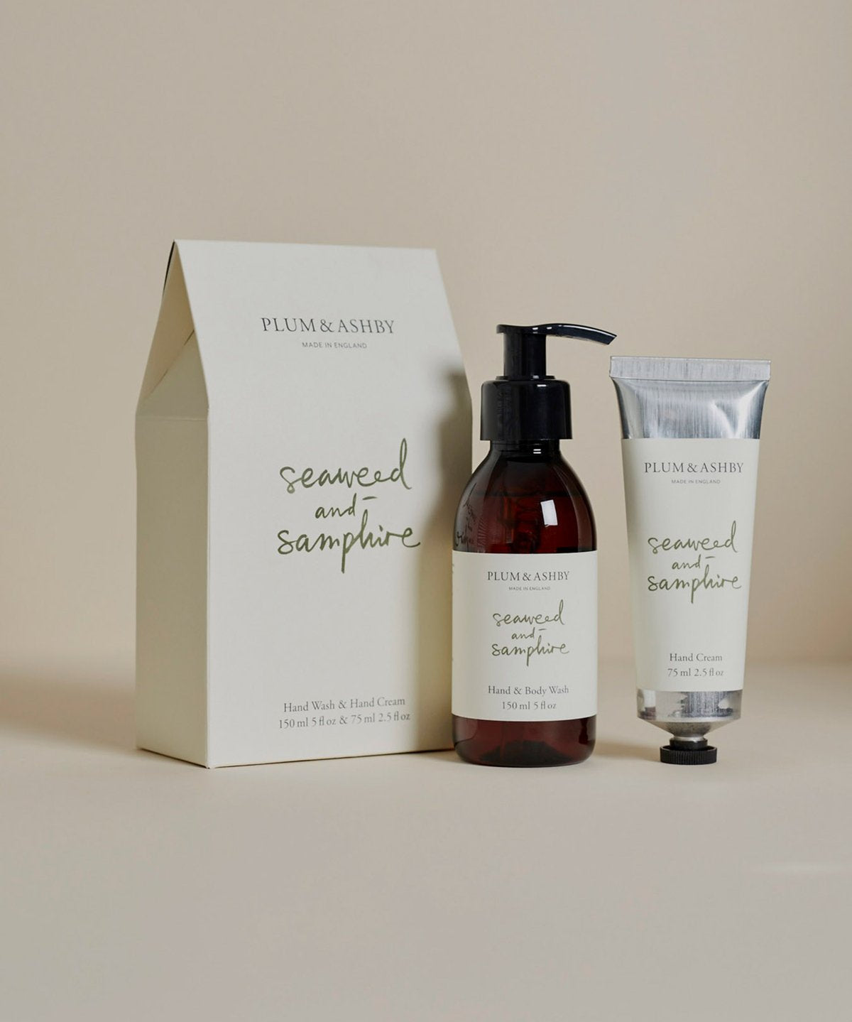 A set of Plum & Ashby seaweed and samphire handwash and hand cream products, with a bottle of hand wash and a tube of hand cream in front of a neutral background, packaged in a beige box with the product names and ingredients listed.