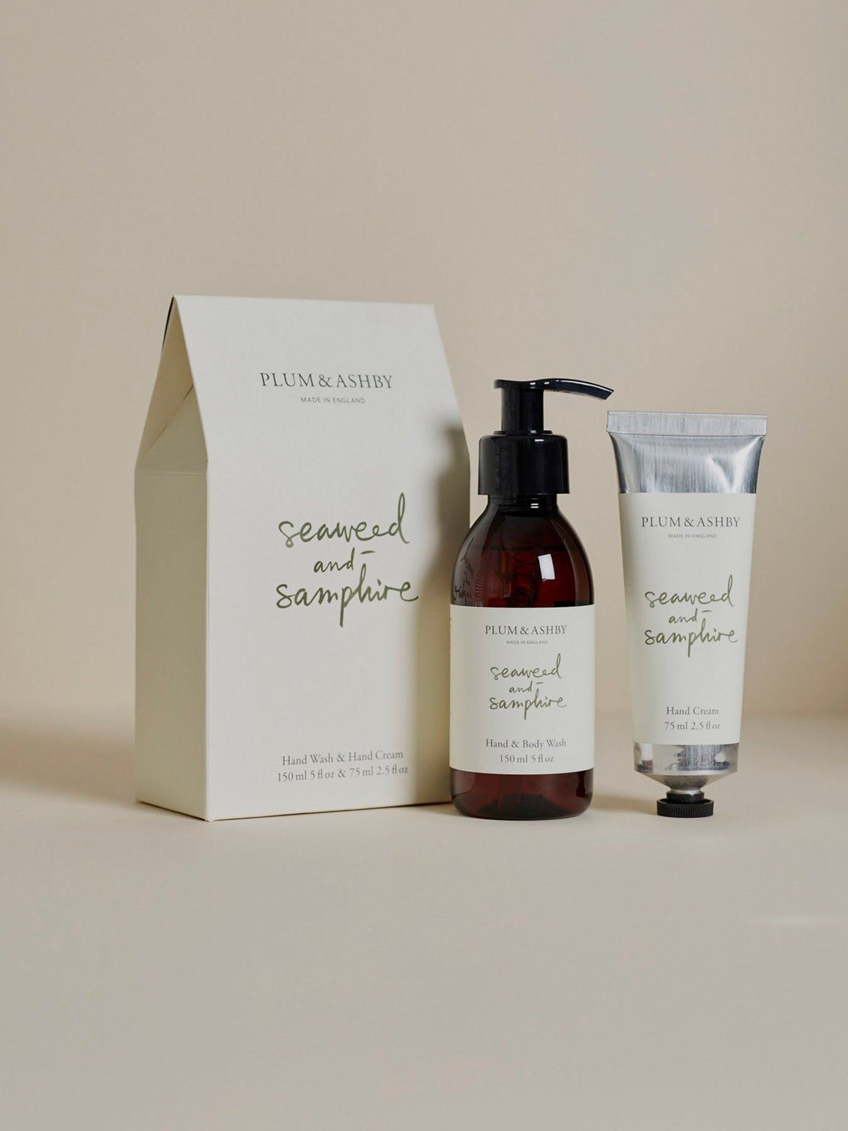 A set of Plum & Ashby seaweed and samphire handwash and hand cream products, with a bottle of hand wash and a tube of hand cream in front of a neutral background, packaged in a beige box with the product names and ingredients listed.