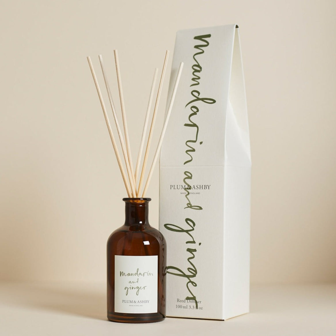 A Plum & Ashby Mandarin & Ginger diffuser with a glass vessel and reeds, displayed next to its packaging box.