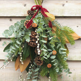 The Nordic Welcome fresh Christmas door swag with blue spruce, magnolia, eucalyptus, pinecones and Marsala red velvet ribbon
